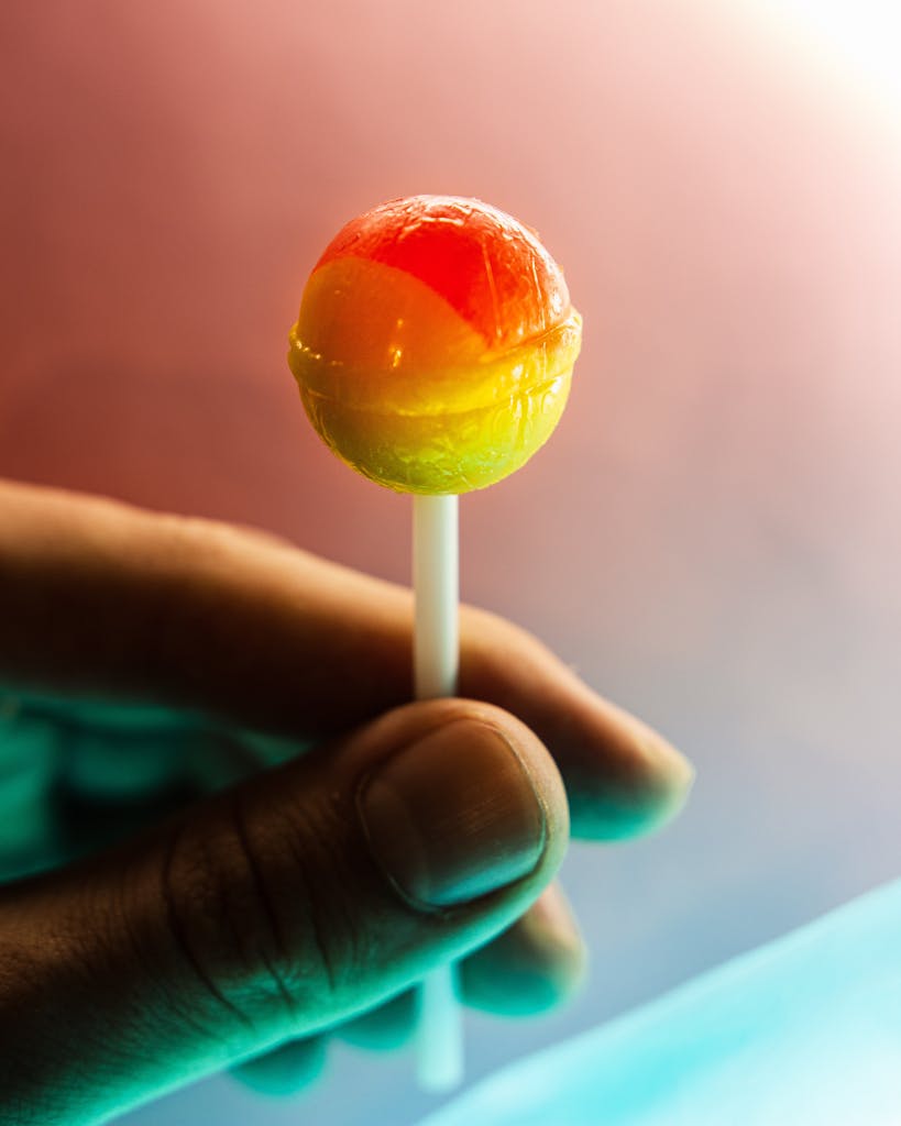 Vivid close-up of a hand holding a colorful lollipop, highlighting its delicious appeal.